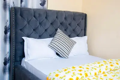 a bed with a black headboard with a pillow on it at Mella home Arusha in Arusha