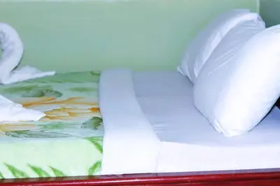 a bed with white sheets and pillows on it at Bamboo Savannah in Arusha