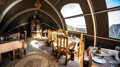 a dining room with tables and chairs and windows at Africa Safari Rift Valley Camping in Magara