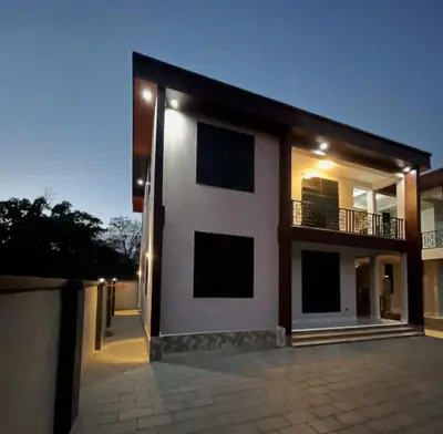a white house with a balcony on the side of it at Stay with Rodjazz in Usa River