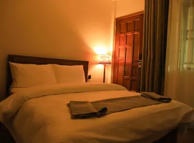 a bedroom with a bed with a robe on it at River House Lodge International in Arusha