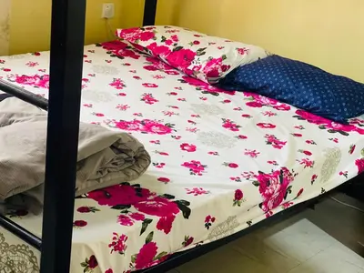 a bed with a flowered sheet and pillows on it at Amani Homestay in Arusha