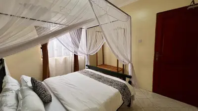 a bedroom with a canopy bed with a window at Ultra Home Hostel in Arusha
