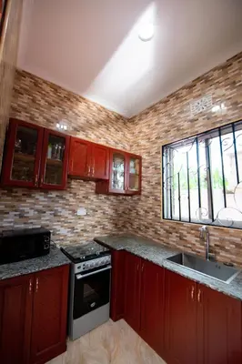 a kitchen with red cabinets and a stove and windows at Private Nest Apartment 2 in Arusha