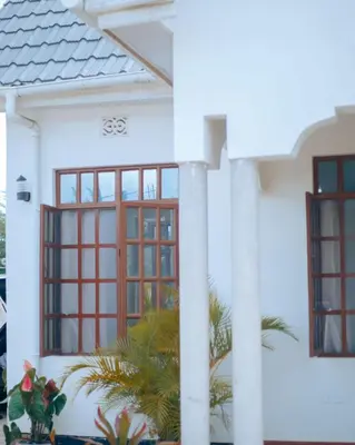 a white house with red windows and plants at Arusha 2bedroom in Arusha