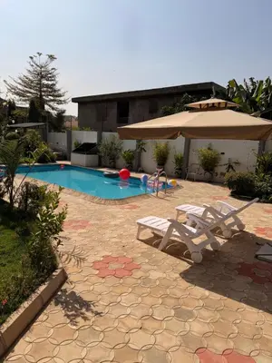 a swimming pool with two chairs and an umbrella at Royal Safary Appartement in Arusha