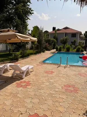 a swimming pool with a table and an umbrella at Royal Safary Appartement in Arusha