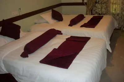two beds with towels and pillows on them at New Charity Hotel International in Arusha