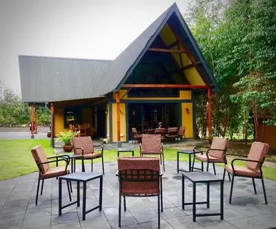 a group of chairs and tables in front of a building at Shamba Lodge Cabin C in Olmotoni