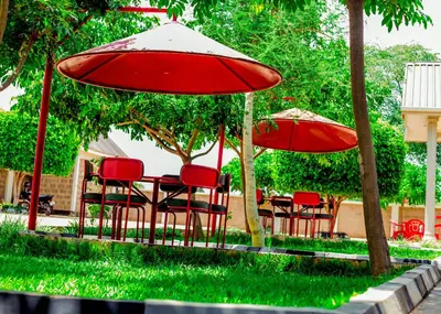 a table and chairs with red umbrellas at Randa Cottages Moshi in Kirua